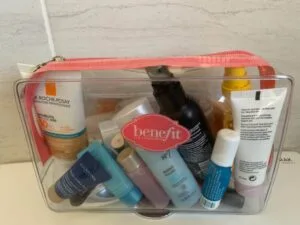 A plastic container showing toiletries as part of hand luggage post. The bag is clear plastic with an orange zipper.