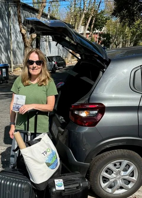 Woman Loading a small grey SUV vehicle with suitcase.