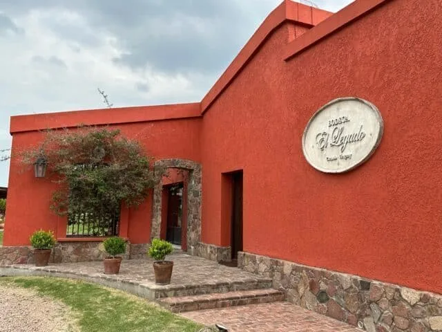 Winery building with stone and brown finish. Decorated with plant pots and shrubs.