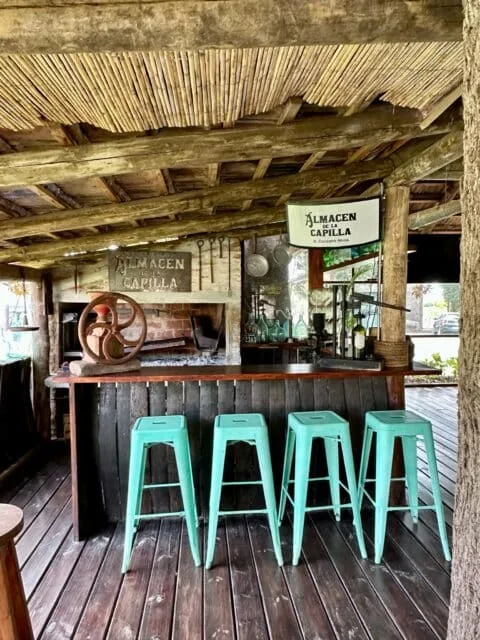 Small wine bar with a thatched roof and blue barstools.
