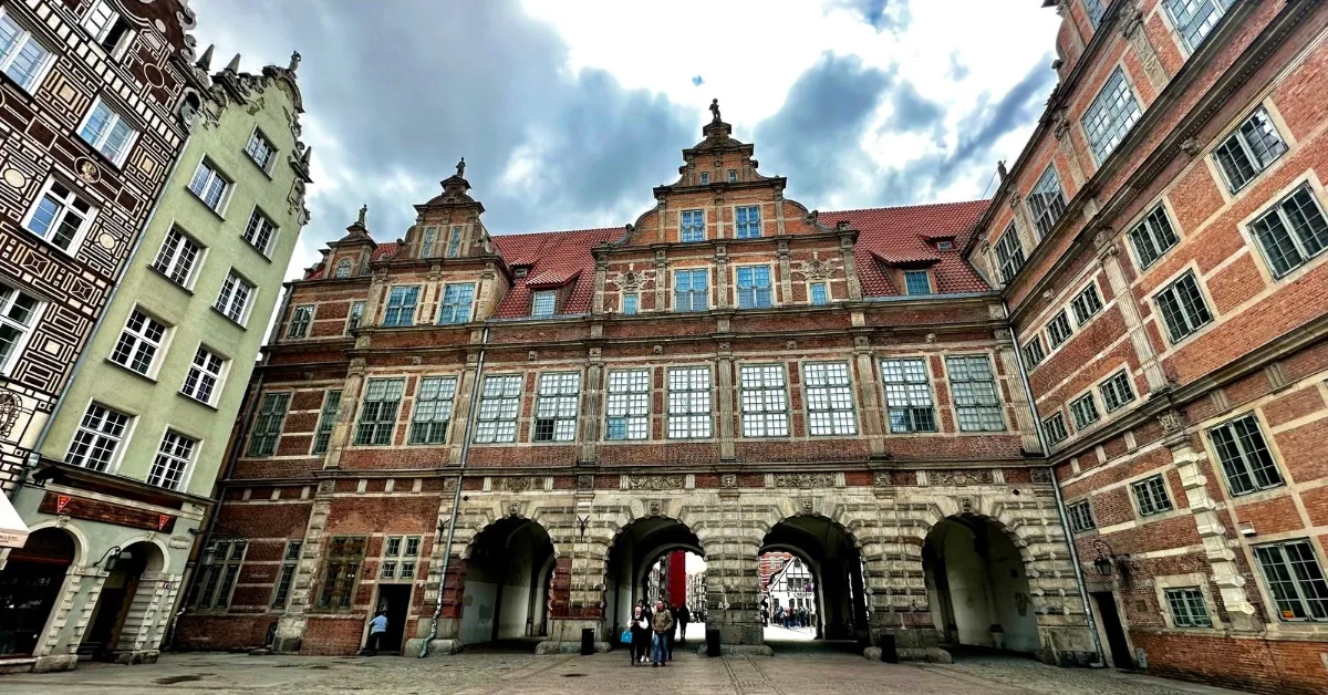 Multiple arches create a route from Old Town Gdansk to the Motlawa River. Above the stone arches are rooms and the top roof is baroque red tile style.