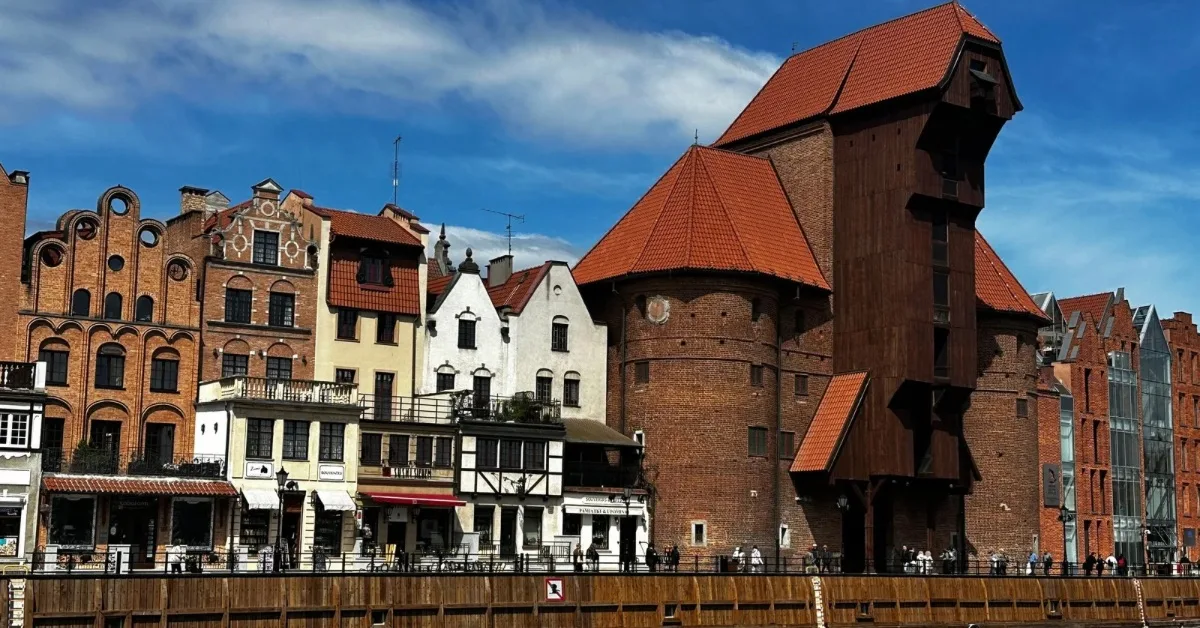Brown brick and wooden structure with no windows is an old crane system. Round buildings are attached to each side of the crane.