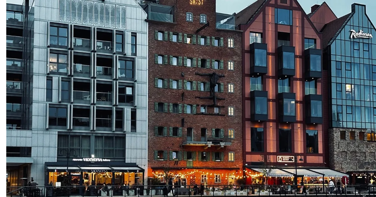 Modern block of waterfront buildings with riverside restaurants lit up.