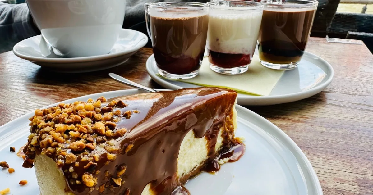 Cheesecake, coffee and a flight of hot chocolate on a table.