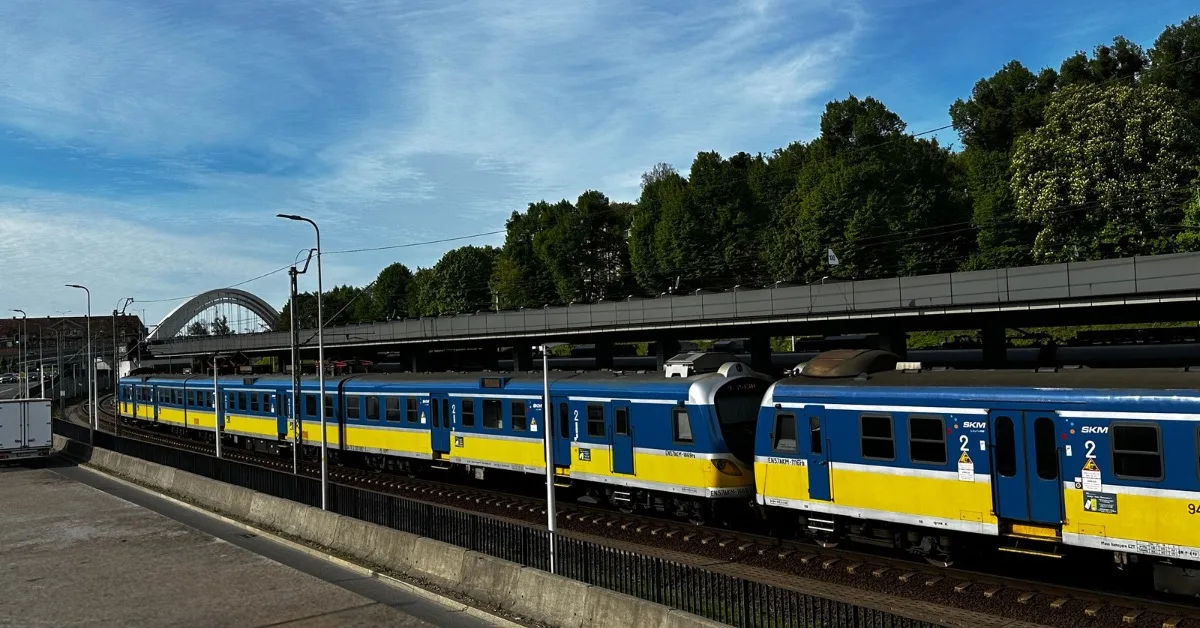 Railway station with a train passing through. It is blue and yellow.