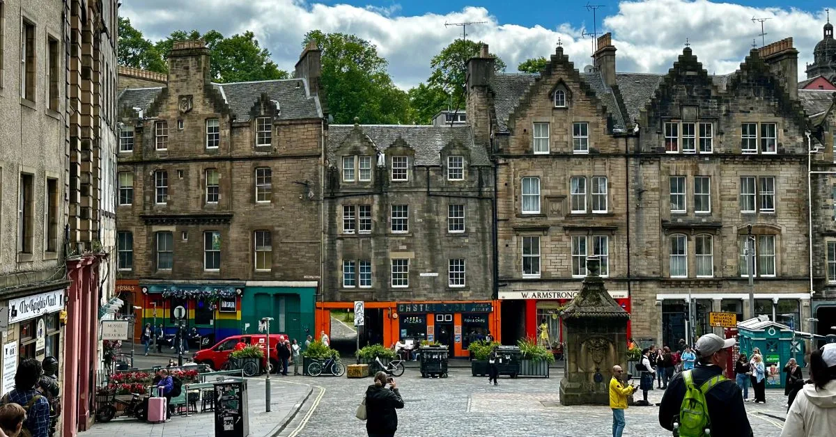 People exploring an old cobbled market area called Grassmarket in Edinburgh.