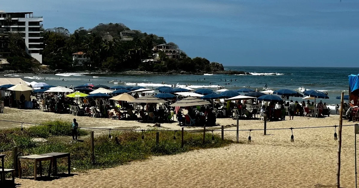 view of a beach full of sun loungers and people relaxing.
