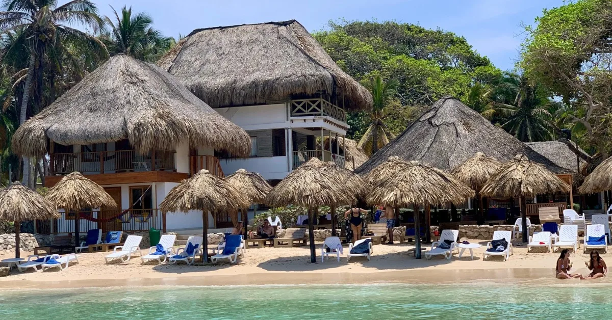 Sun loungers on a sandy beach with thatched umbrella shade.