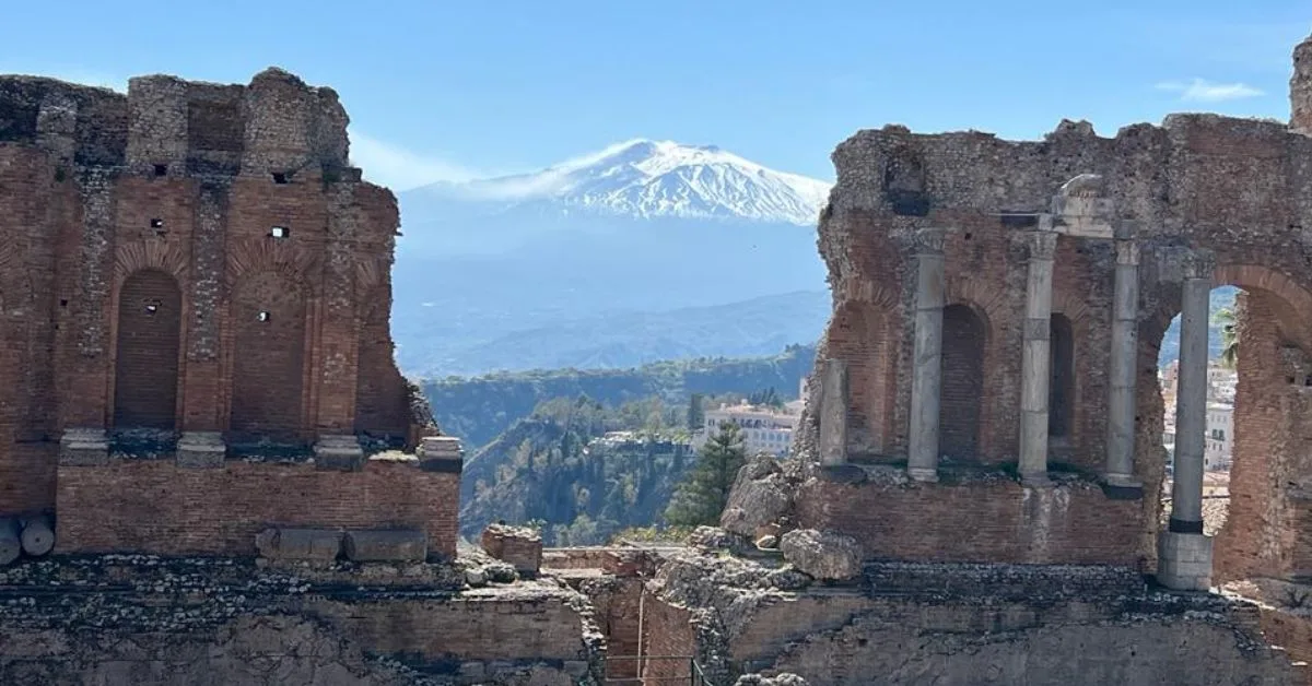 Roman ruins part of amphitheatre with Mount Etna in the background