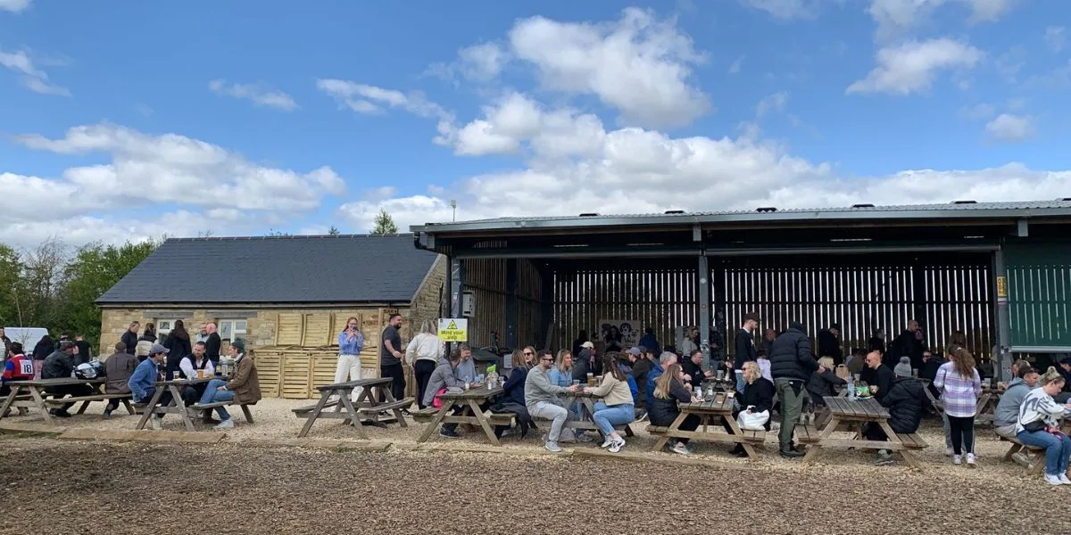 People sitting a a farm cafe outdoors drinking and eating.