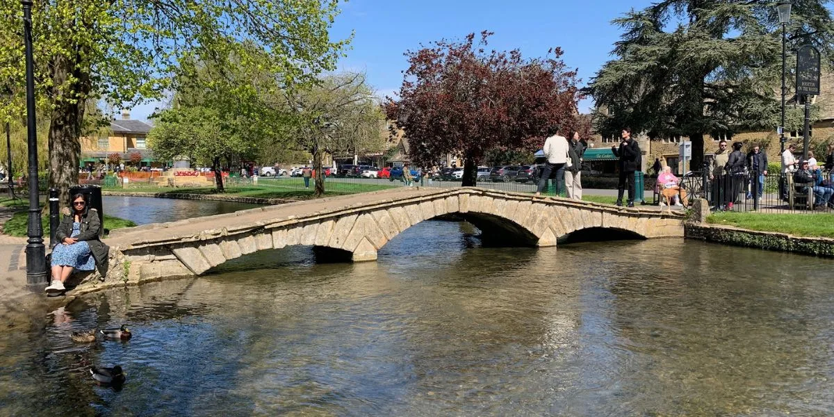 The stone bridges over a river with people walking over.