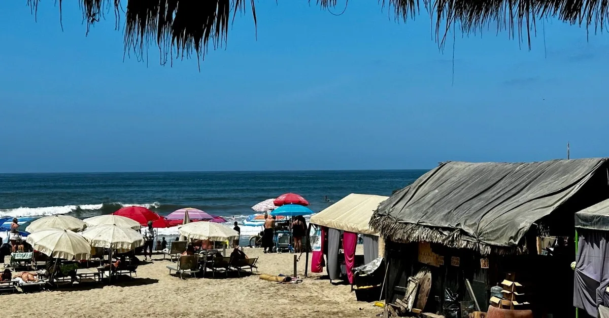 Parasols and beach huts on a sandy area.