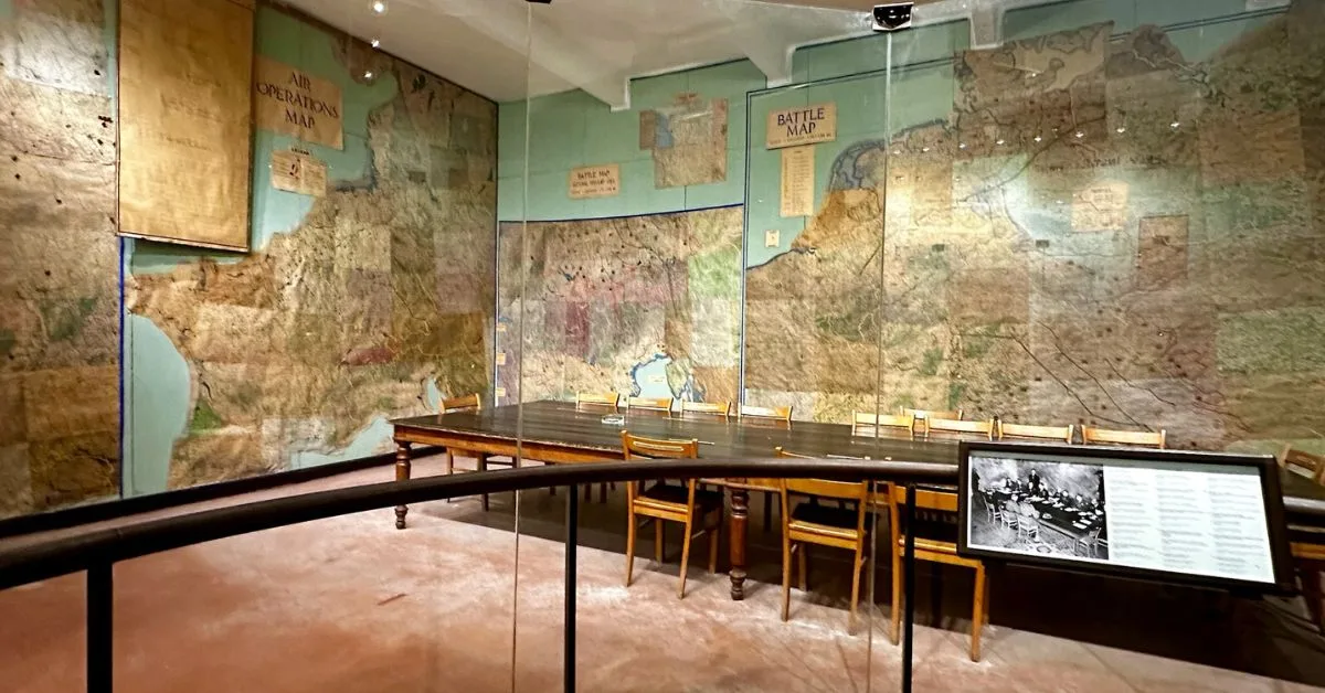 A room with maps on the walls and table chairs where World War 2 surrender was signed.