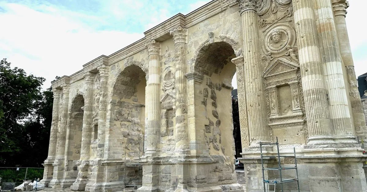 Roman archway gate in Reims with columns and stone carvings.