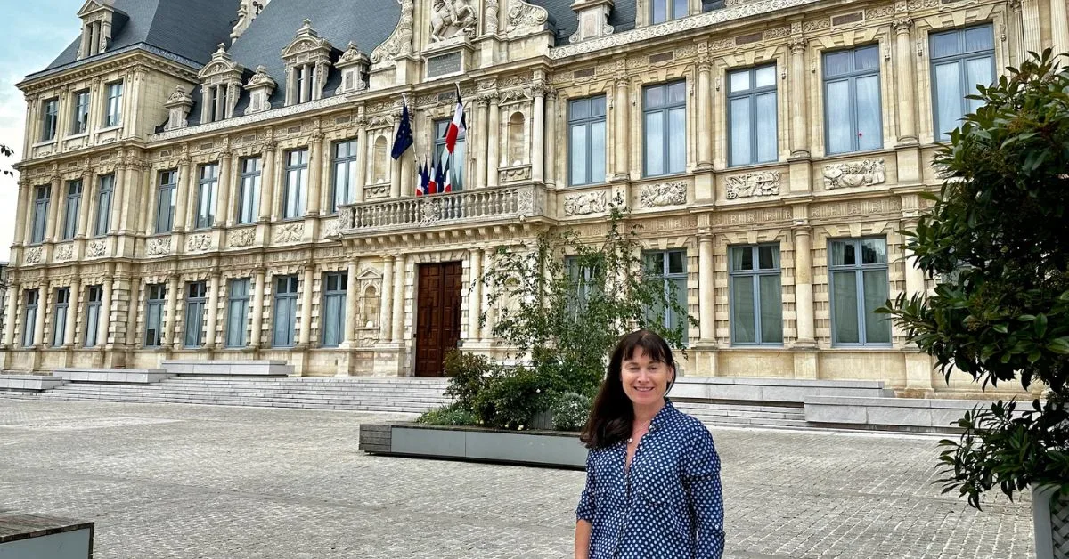 Woman standing in front of a large building which is the town hall in Reims France.