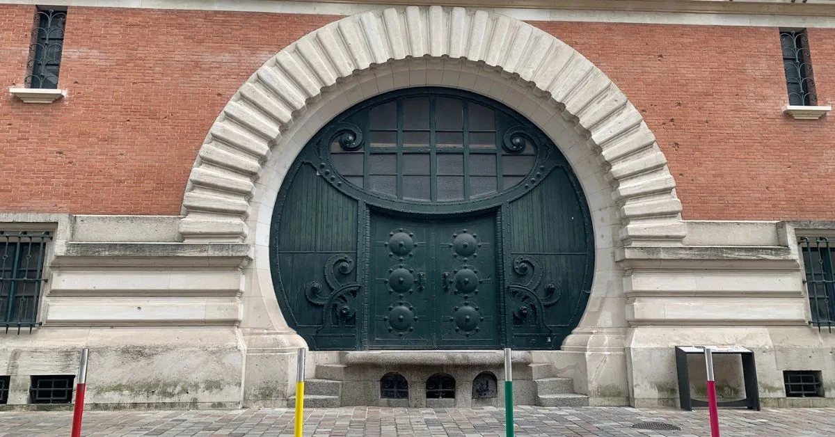 A large arched green door entrance to Taittinger Champagne House in Reims.