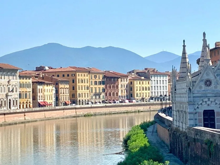 River waterfront of Florence, Italy, with red tiled houses rising next to the water.