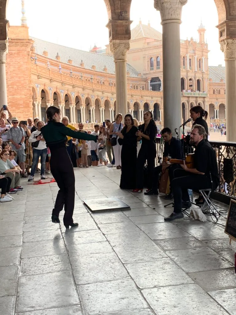 A man is playing guitar in Seville and others dance traditional flamenco dances.