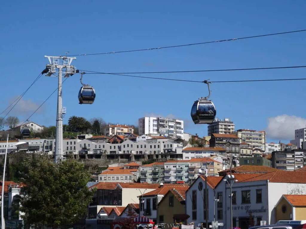 Gondola ride over Porto, Portugal. Two gondolas are moving over the red-tiled rooftops of the central city.