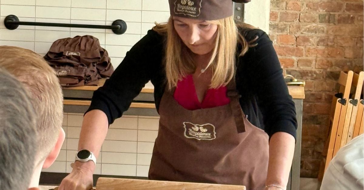 Woman rolling out dough in a bakery setting.
