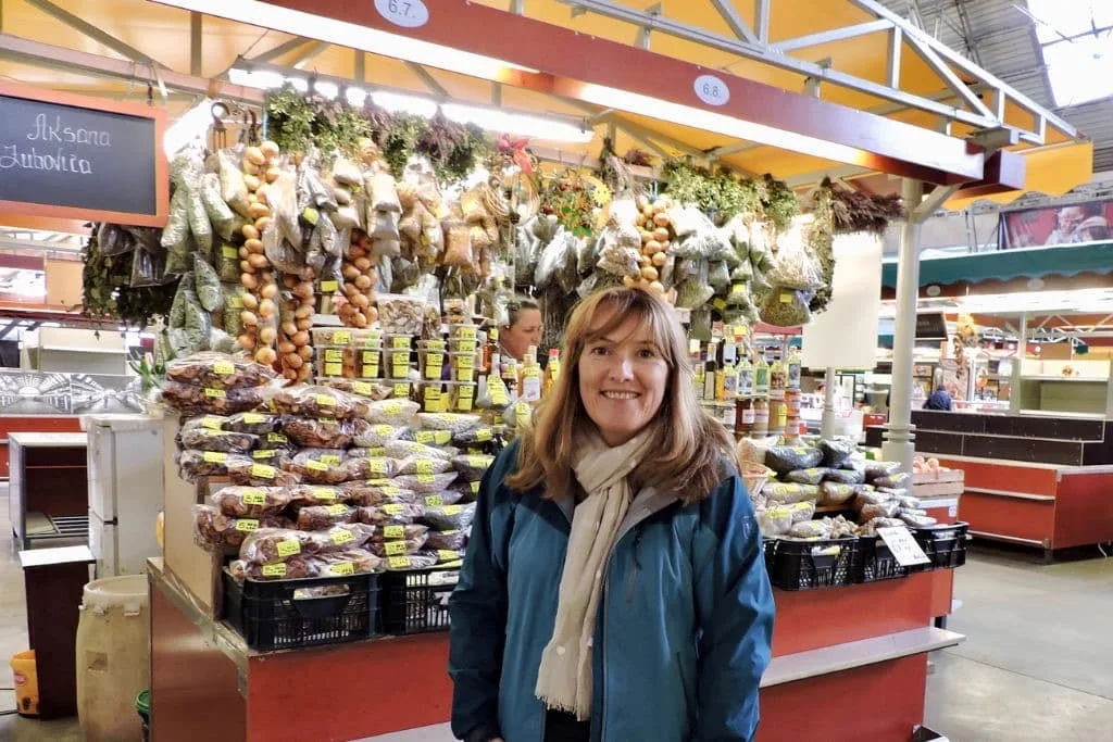 Women standing at a market stall and behind her are local produce.