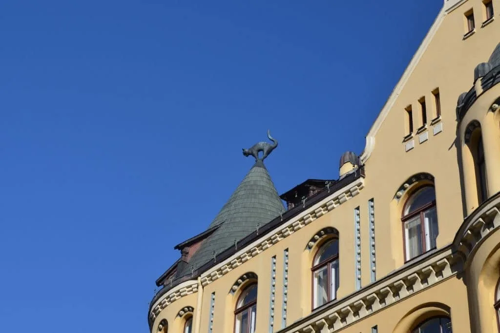A building has a statue of a black cat on top of its roof.