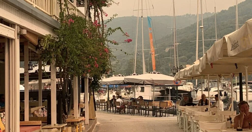 Promenade with upmarket restaurants on the side looking out to the bay where boats are moored up