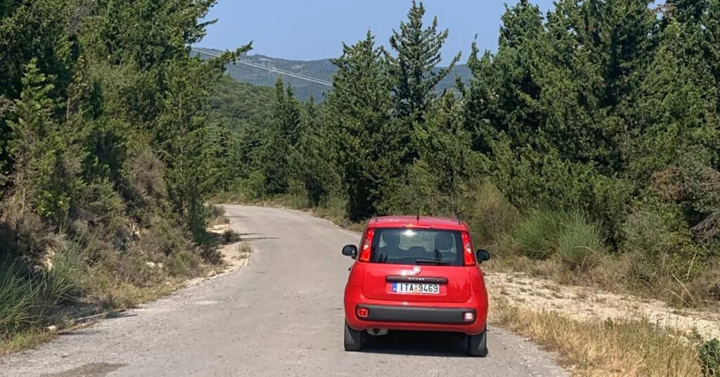 Red car parked on a hill road with no road markings