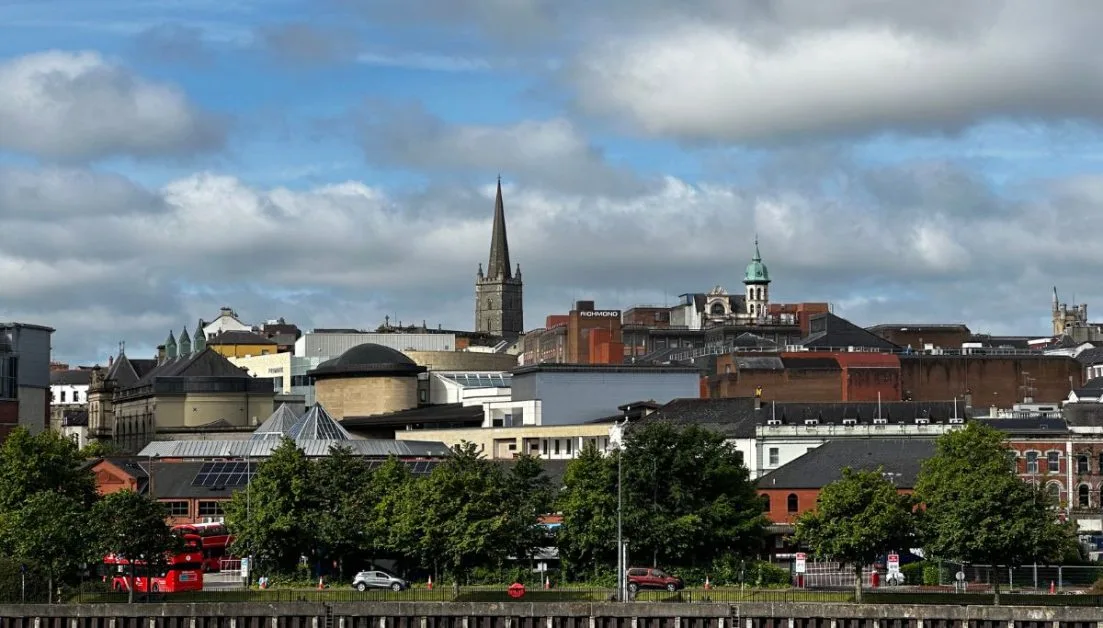 A tall church steeple and other roofs of town buildings in Derry Northern Ireland.
