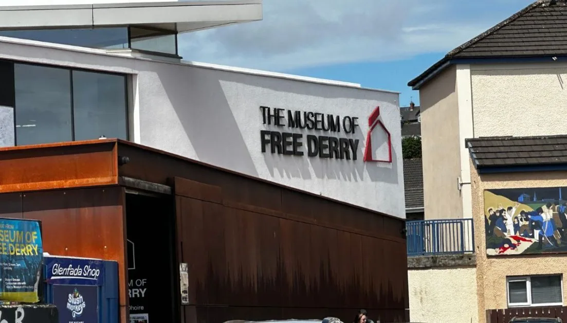 The Museum of Free Derry signage and a small mural depicting local people gathering around a victim of troubles.