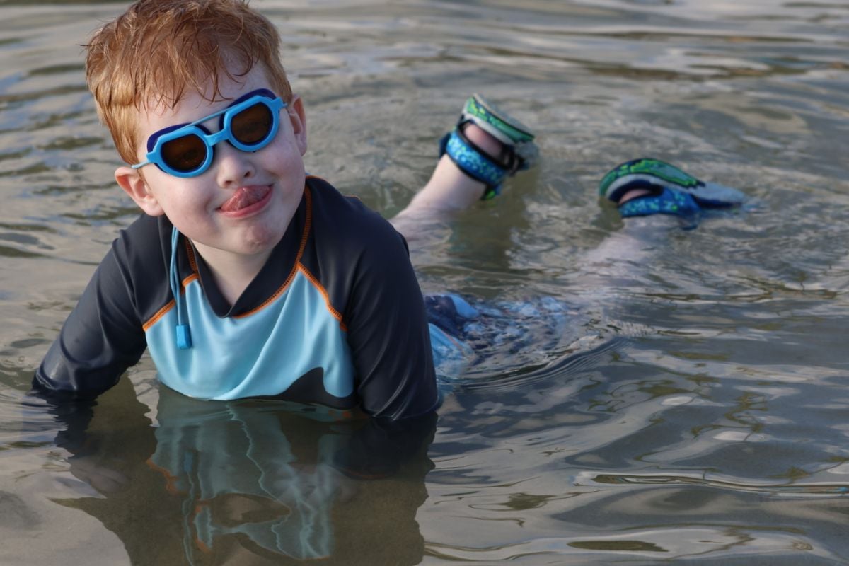 Boy swimming with goggles in the calm waters at Poipu Beach, Kauai