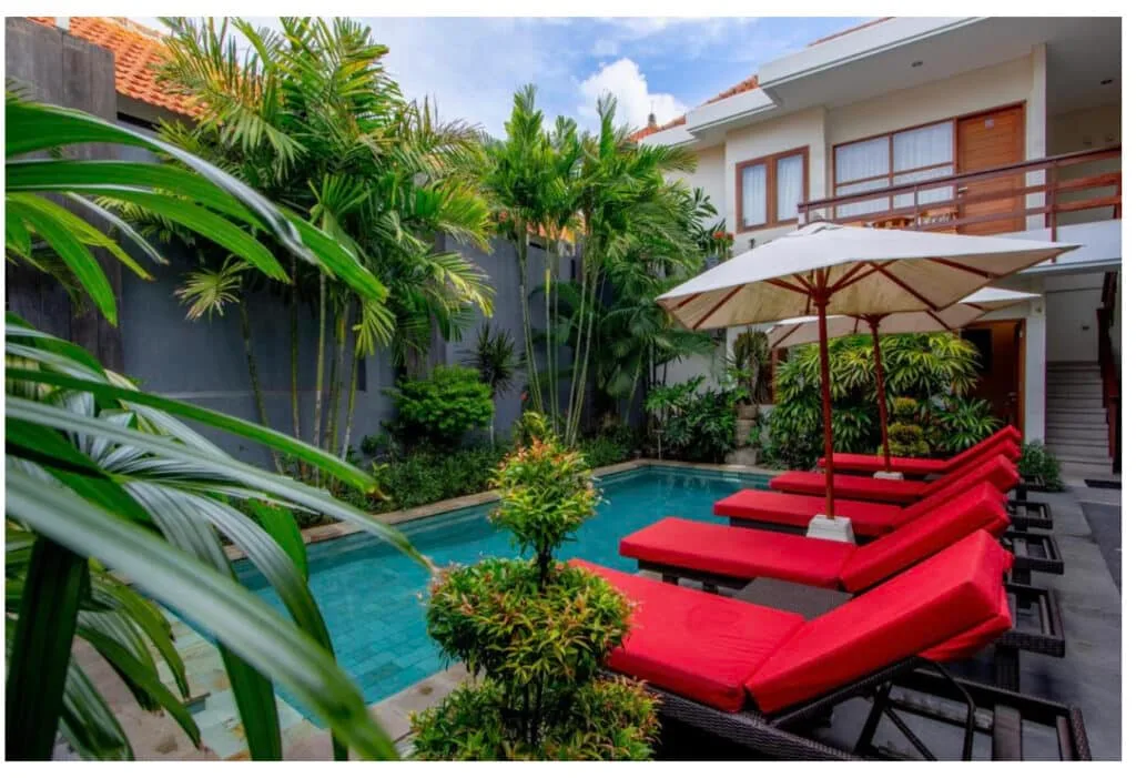 Pool Area and Red Sun Loungers Around the Swimming area. Lush foliage gives privacy to guests.