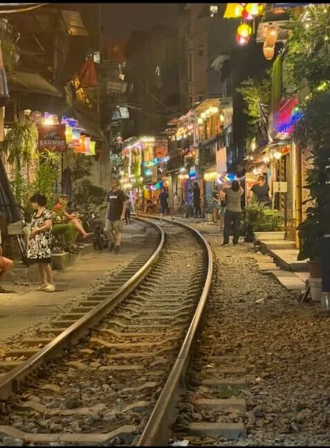 A single railway line going through a busy street at night in Hanoi