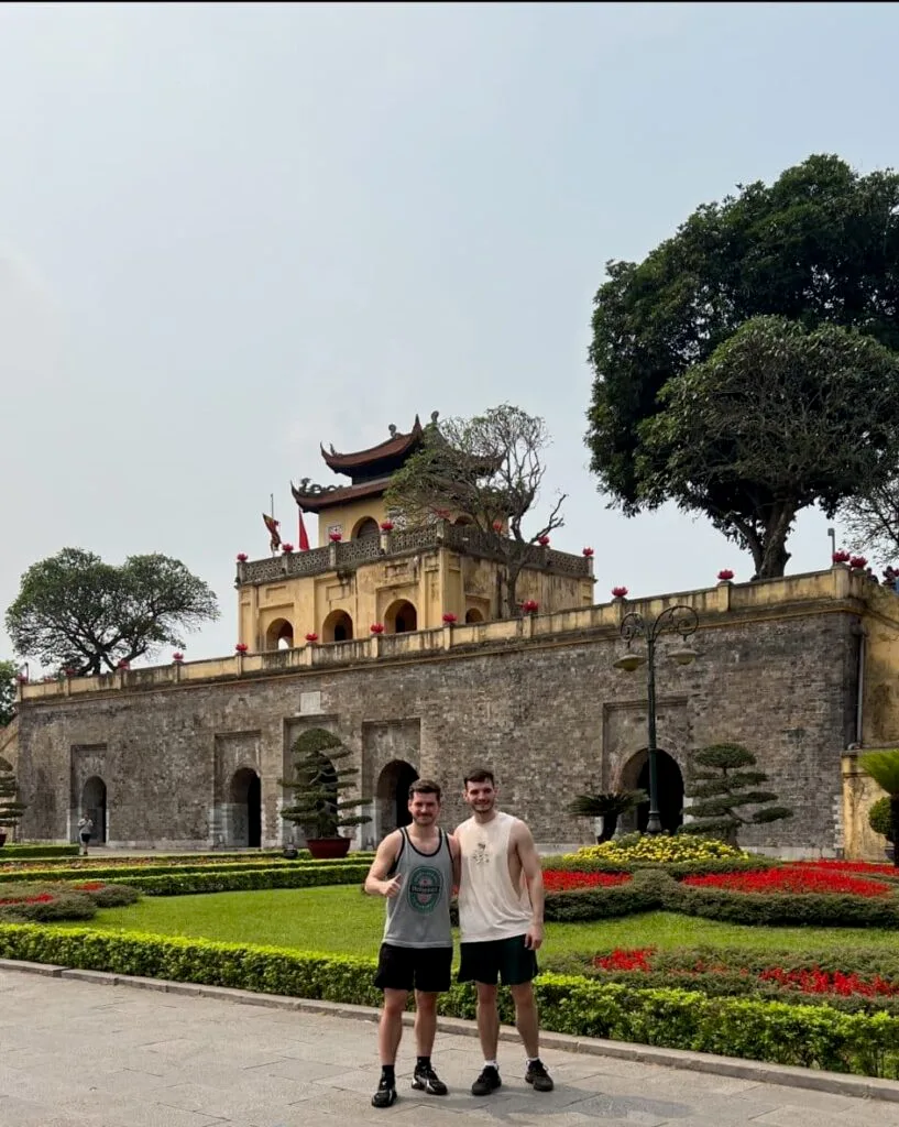 Two tourists standing in Hanoi outside the formal Communist HQ building.