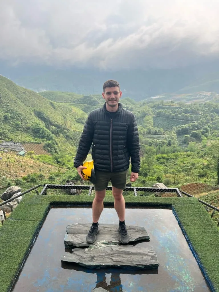 Traveler standing on a high level platform in Sapa, Vietnam with forest views behind.