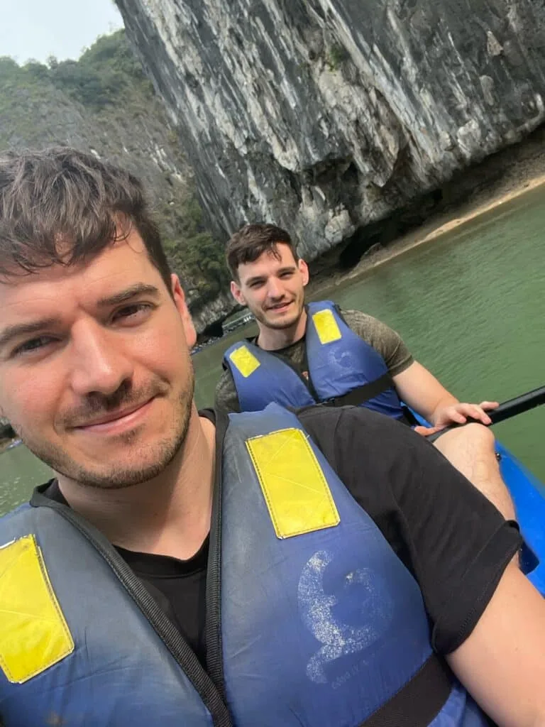 Men in kayaks paddling around formations in Ha Long Bay Vietnam.