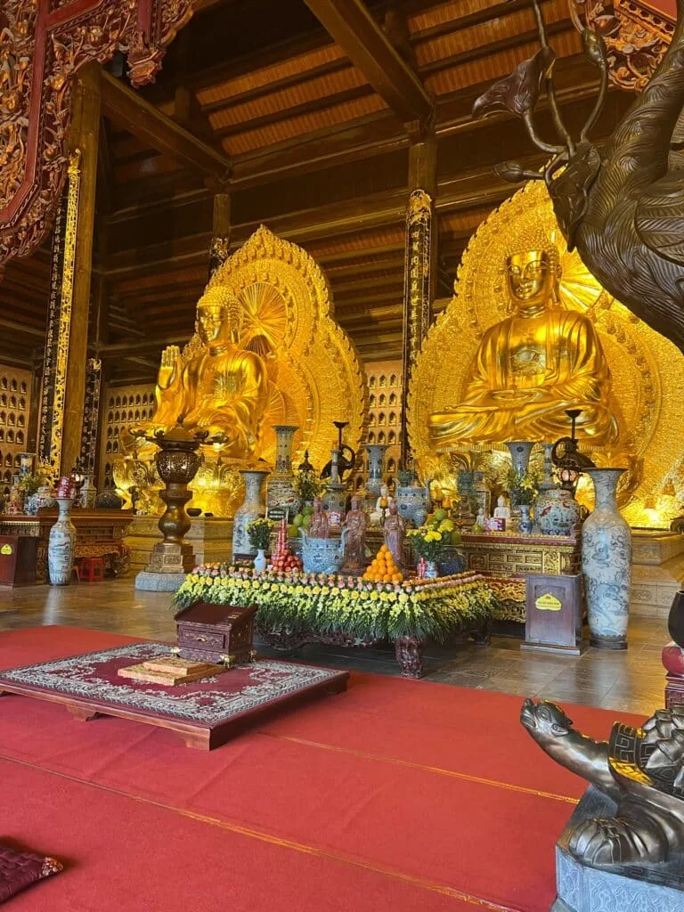 Gold figures in a Vietnamese temple and in front of them candles and red carpet