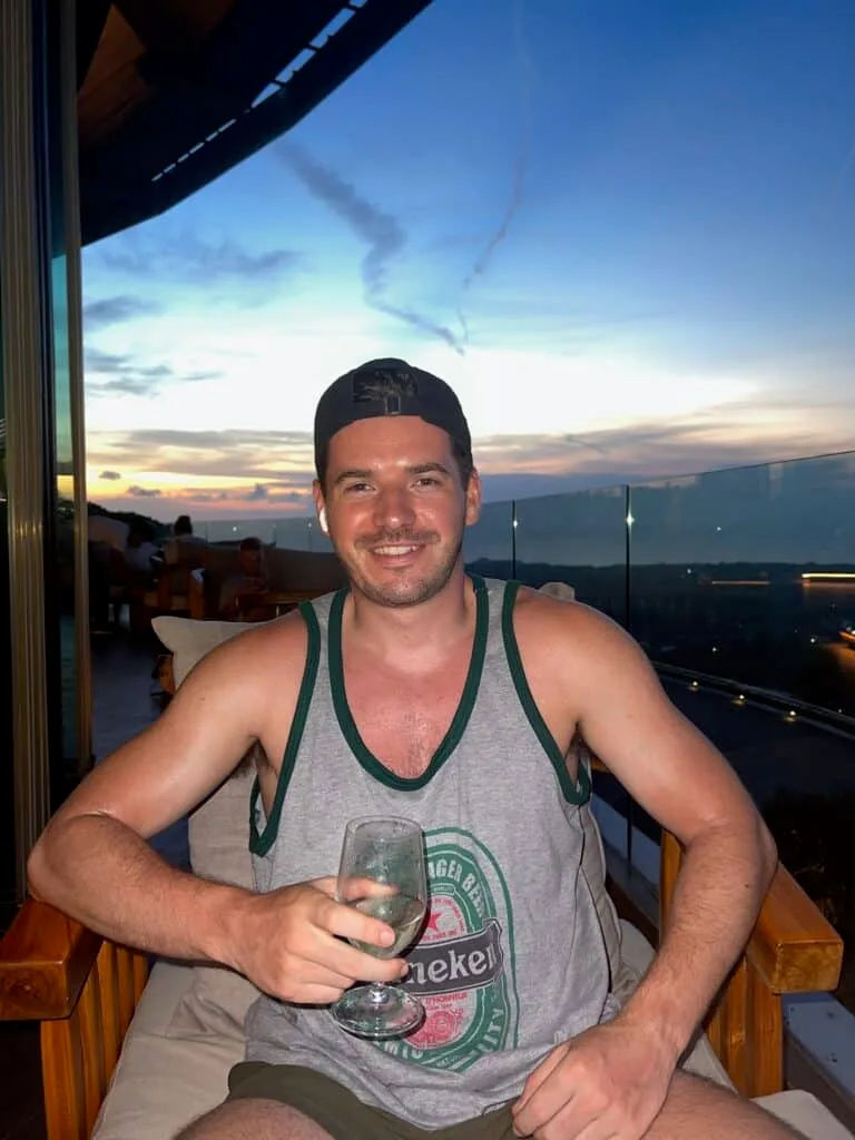 Alex, traveller in Vietnam with a beer. Sun setting behind him.