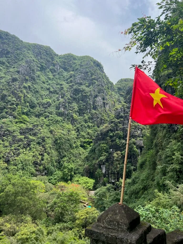 Vietnam flat on a monument in Sapa Region flies above a thickly forested area.