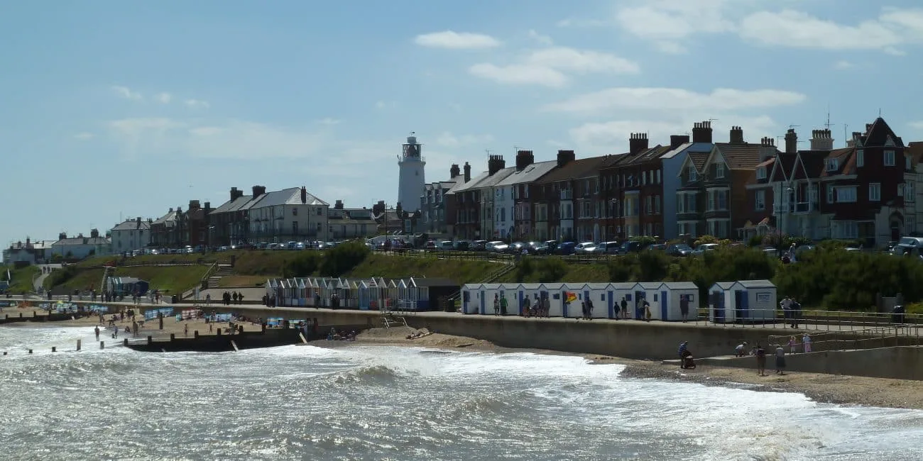 Series of beach huts on a concrete esplanade that visitors can rent while enjoying the beach at a small English seaside town - Southwold in Suffolk.