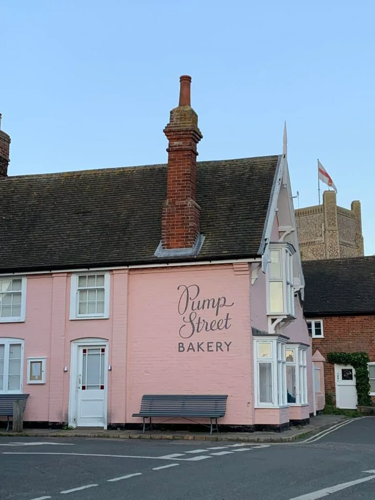 A pink painted building which is advertising itself as a bakery.