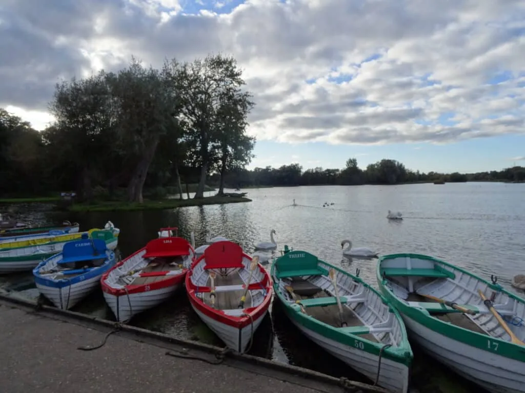 Boats - red, green and blue, sit waiting for passengers at a lake.