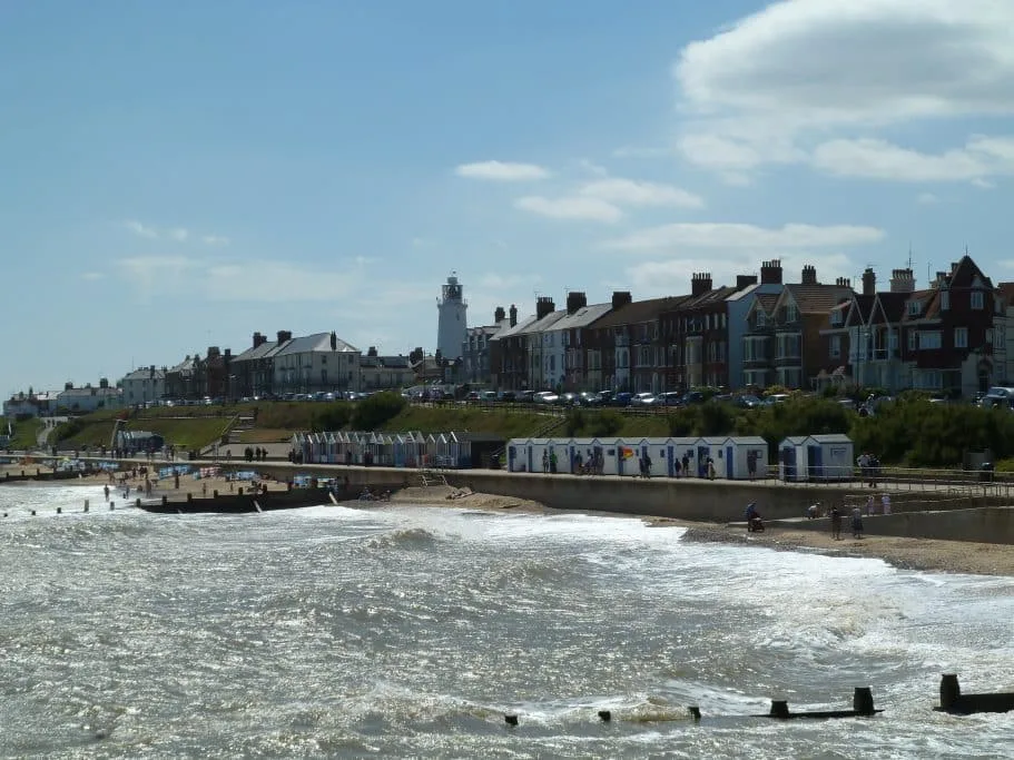 Series of beach huts on a concrete esplanade that visitors can rent while enjoying the beach at a small English seaside town - Southwold in Suffolk.