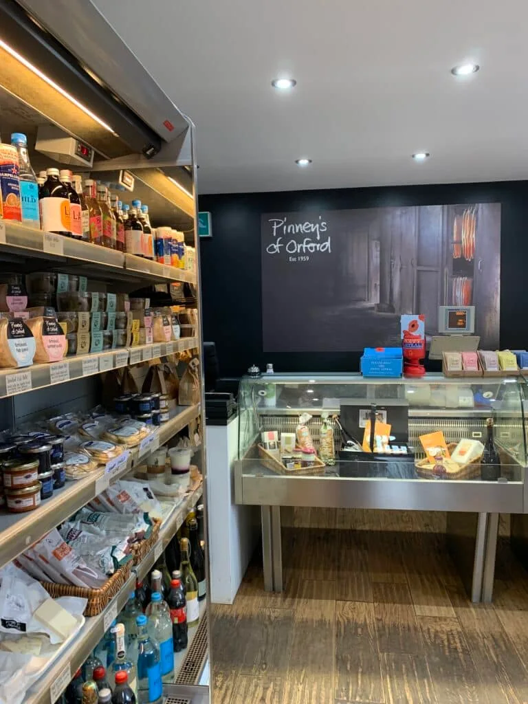 A small farm shop with shelves of local produces including jams, drinks and cheese.