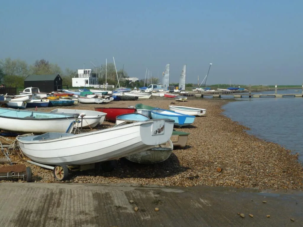 Small wooden painted fishing Boats moored on a sandy beach edge in Suffolk, UK