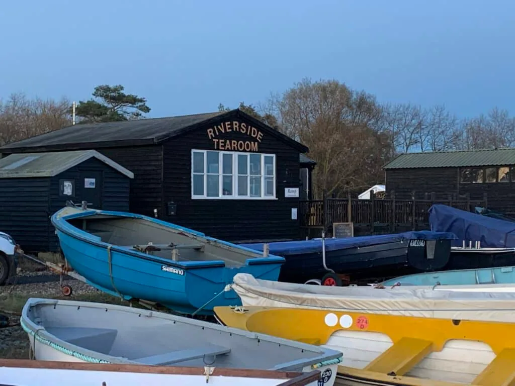 Yellow, Blue and White Wooden boats are moored in front of a tea room.