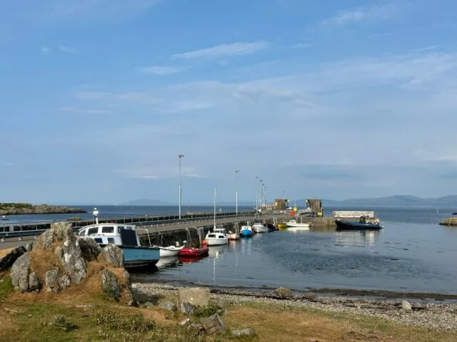Views of an island harbour and ferry port on the isle of Colonsay Scotland. Small local boats are tied up along the stone harbor walls.
