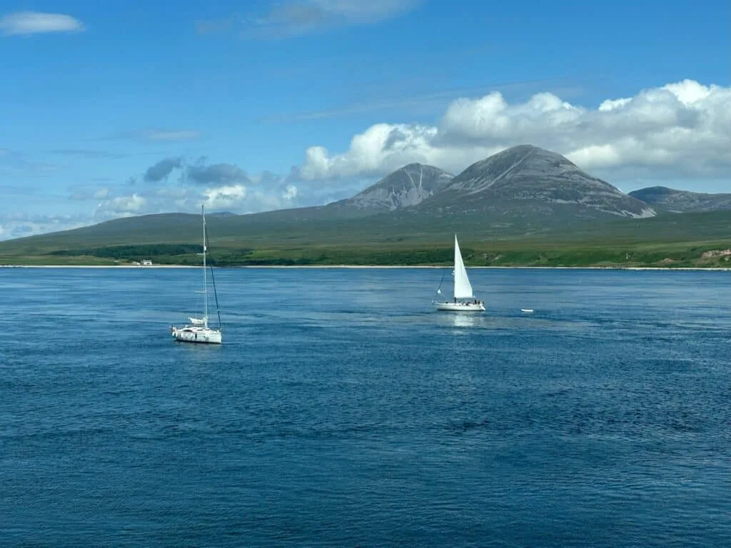 Views from Islay to Jura with sailboats and Jura mountains behind the loch.