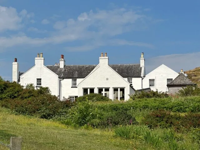 Whitewash Inn sitting in ground of green bushes and surrounded by fields of grass