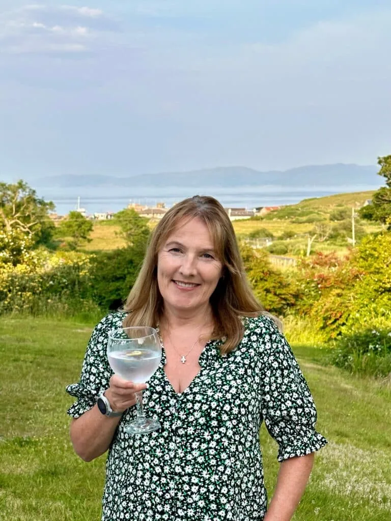 Woman with glass standing in garden on Colonsay Scotland